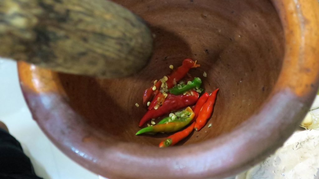 Zubereitung von Yam Moo Yor: frische Chilis im Mörser